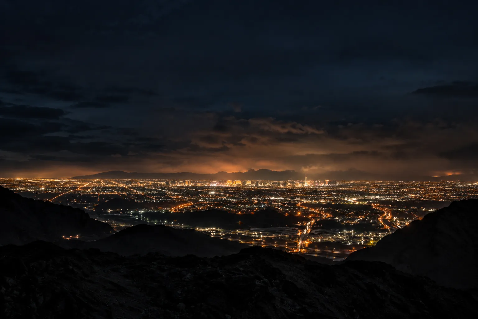 Henderson and the Las Vegas valley at night, seen from the dark desert hills above the city